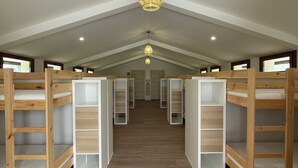 A room with bunk beds, wooden flooring, and a central hanging light fixture. - Larraitz Aterpetxea (PV)