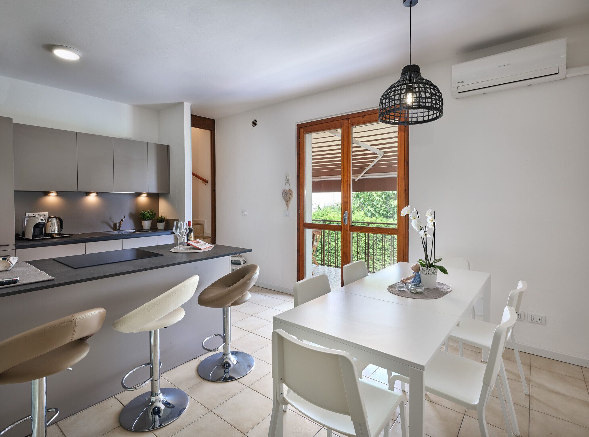 A modern kitchen with a central island, bar stools, and a dining area with a white table and chairs.