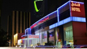 Ein Hotel mit auffälliger Beschilderung in Arabisch und Englisch, großen Glasfenstern und einem modernen architektonischen Design.