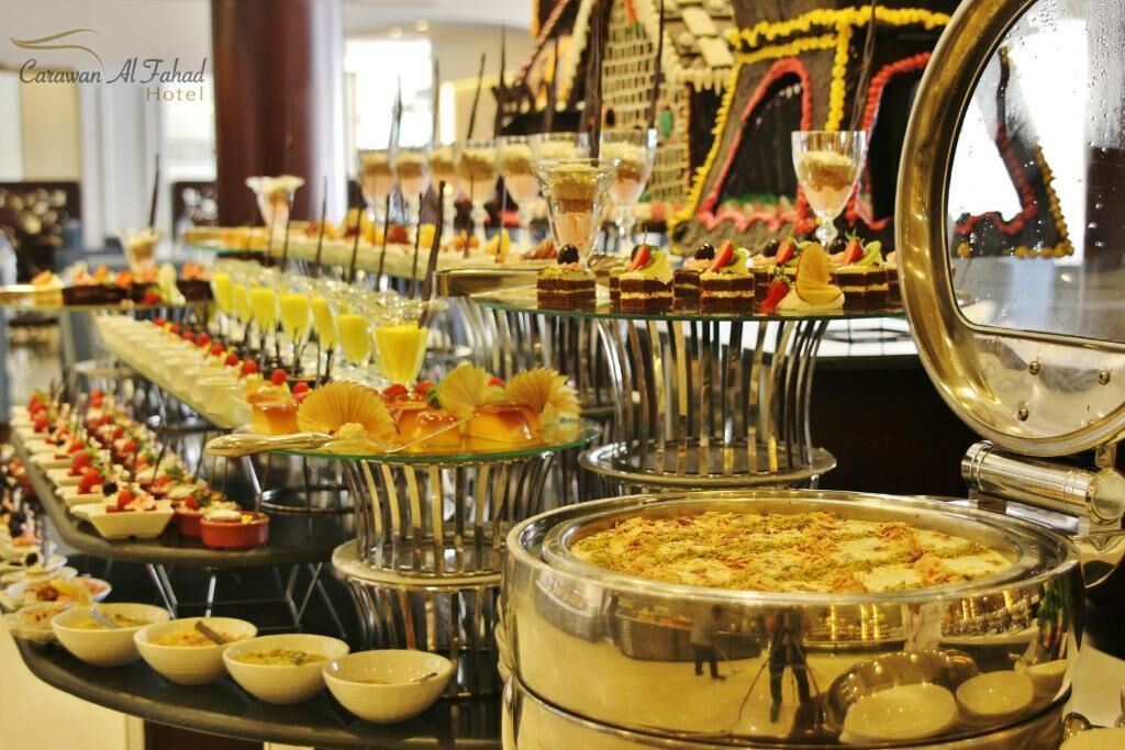 A buffet with various dishes and desserts, including a large pie and several glass dishes with food.