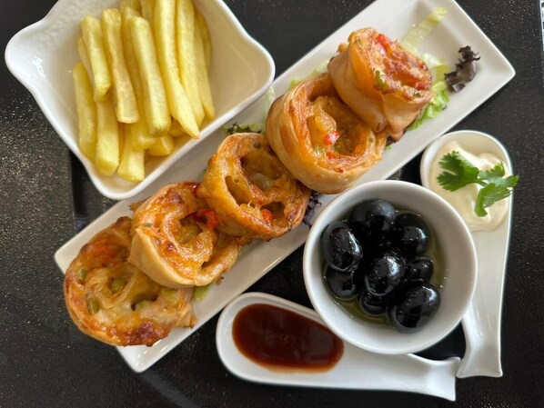 A plate with fried food, a bowl of olives, and a small dish of sauce. - Carawan Al Fahad Hotel (Riyadh)