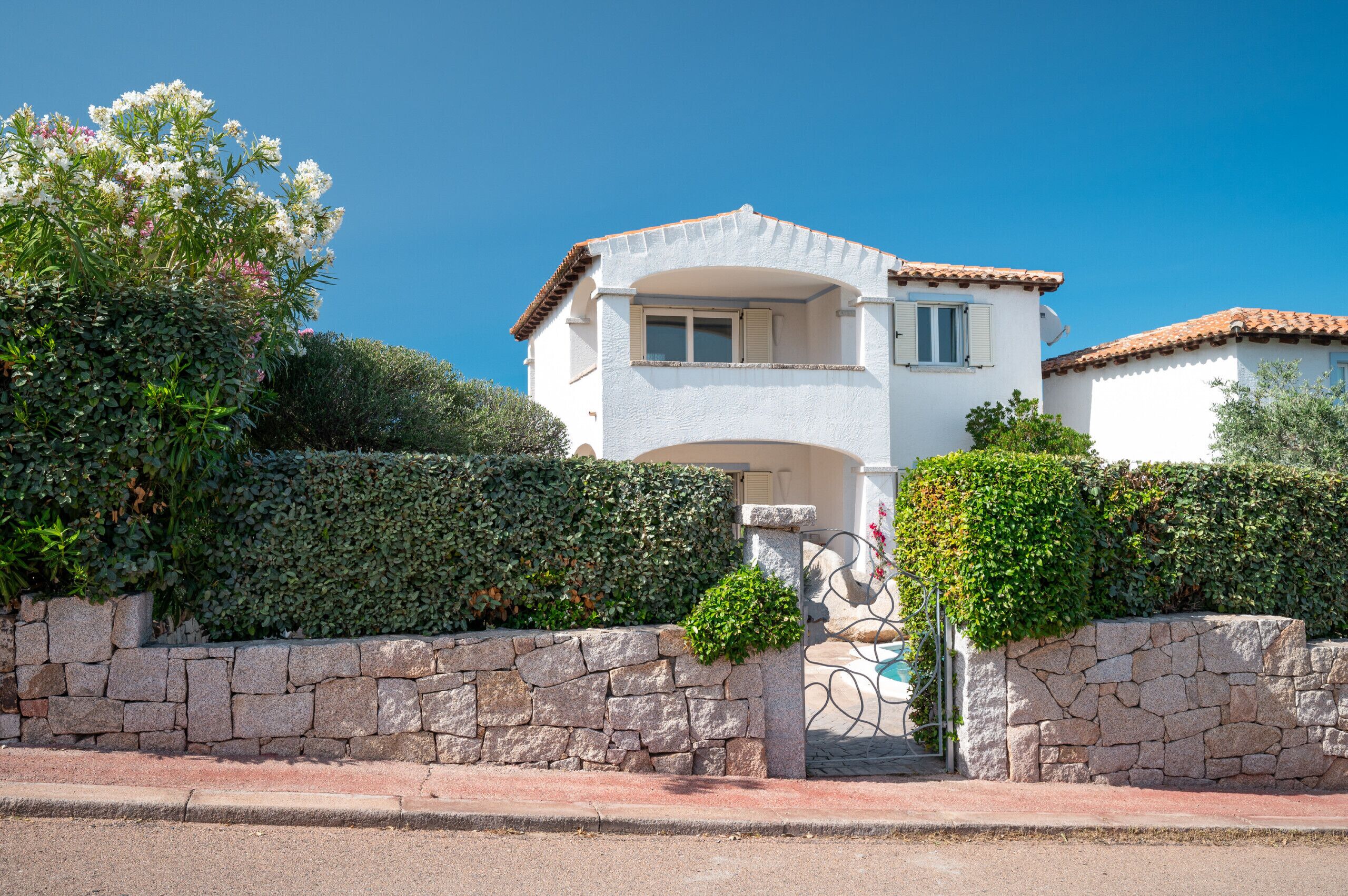 A two-story house with a stone wall and a tiled roof.