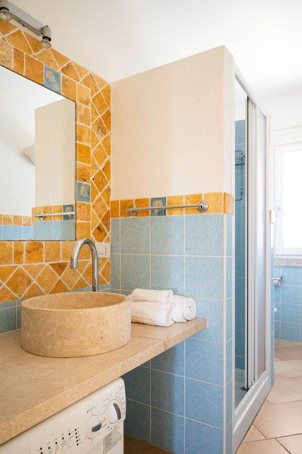 A bathroom with a sink, mirror, and shower.