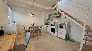 Een kleine keuken met een eethoek, een trap en een raam met zonwering.