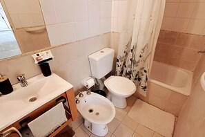 Een badkamer met toilet, bidet, wastafel en bad.