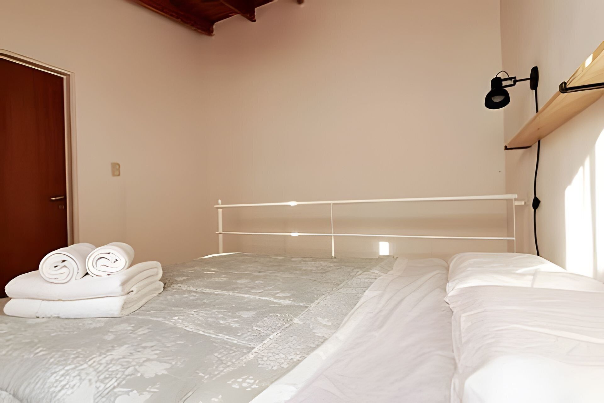 Ein Schlafzimmer mit einem Bett, einer Holztür und einer Wandlampe.