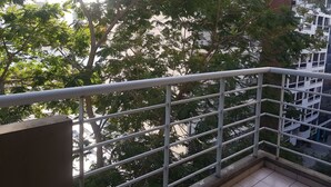 Ein Balkon mit Metallgeländer, der auf eine Stadt mit Bäumen und Gebäuden blickt.