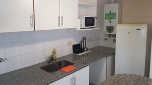 Eine Küche mit weißen Schränken, einer Granit Arbeitsplatte, einer Mikrowelle, einem Wasserspender und einem Kühlschrank.