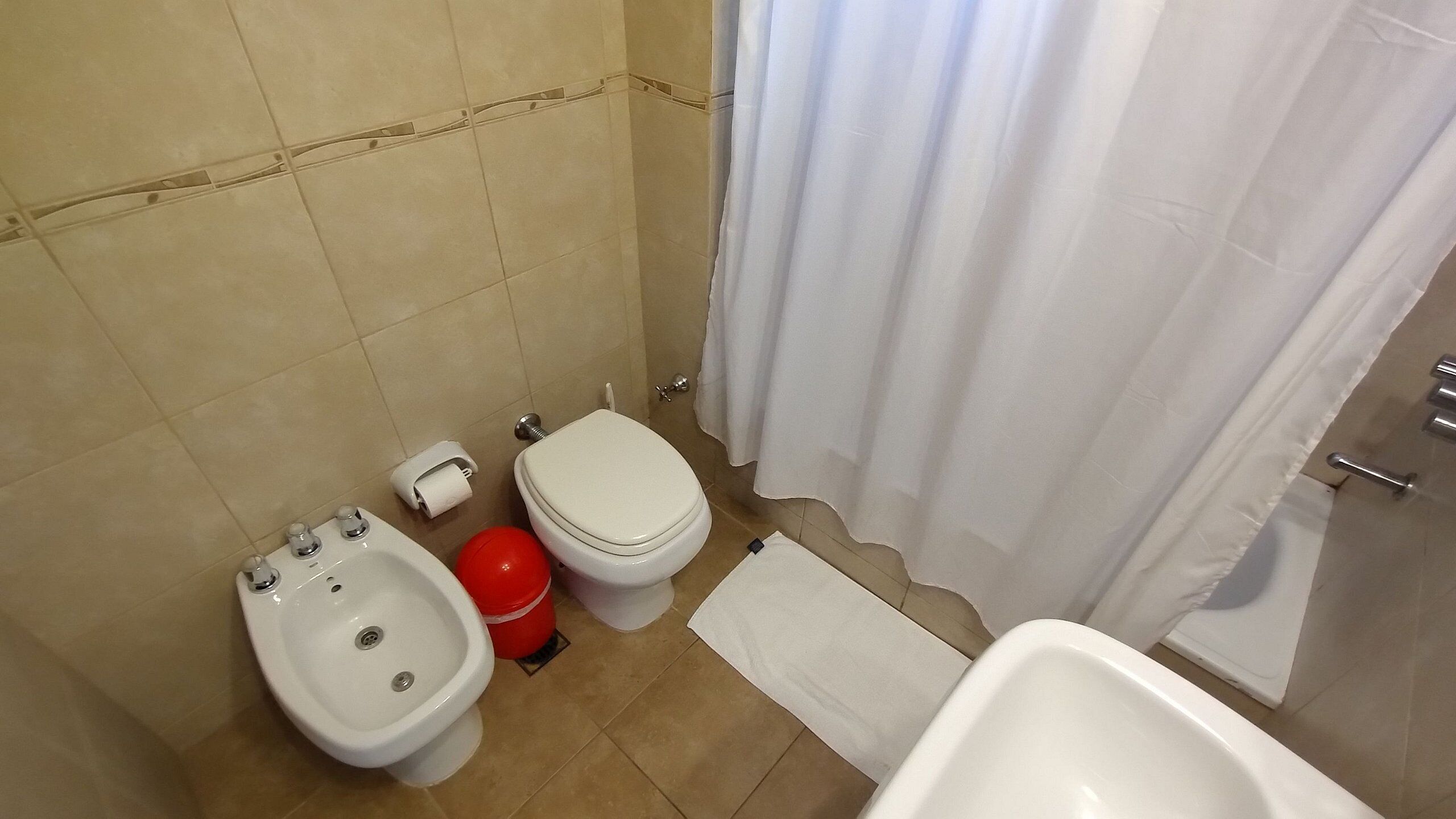 Een badkamer met toilet, bidet en bad.