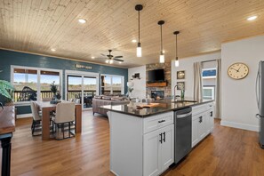 A spacious kitchen with a central island, wooden ceiling, and pendant lighting.