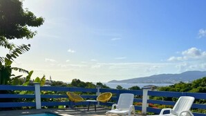 A poolside dining area with a table set for two, two chairs, and a view of the sea and mountains. - T3 private pool - Paprika -Terrasses de la wallon (Les Trois Ilets)