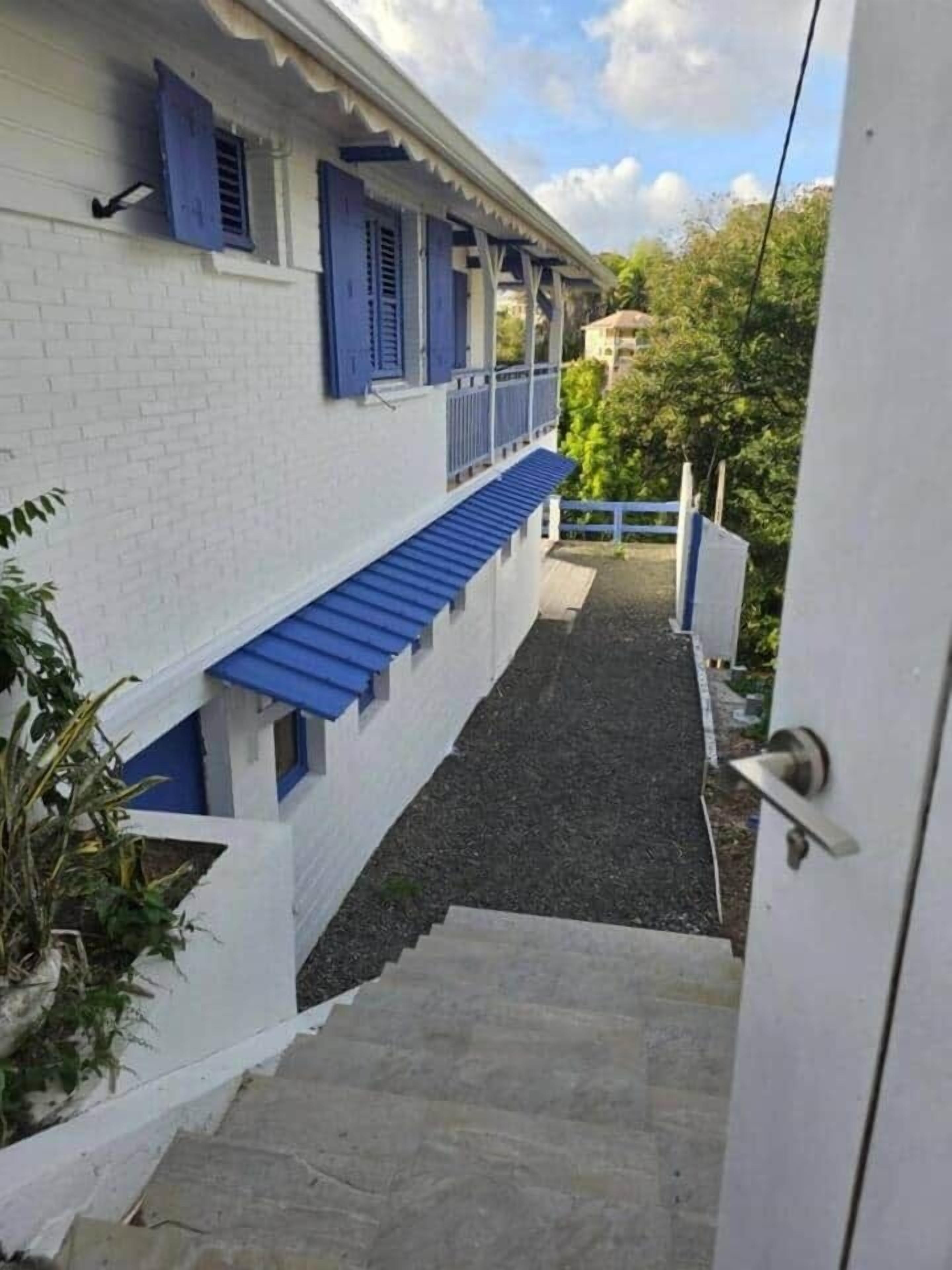 A white building with blue shutters and a covered porch.