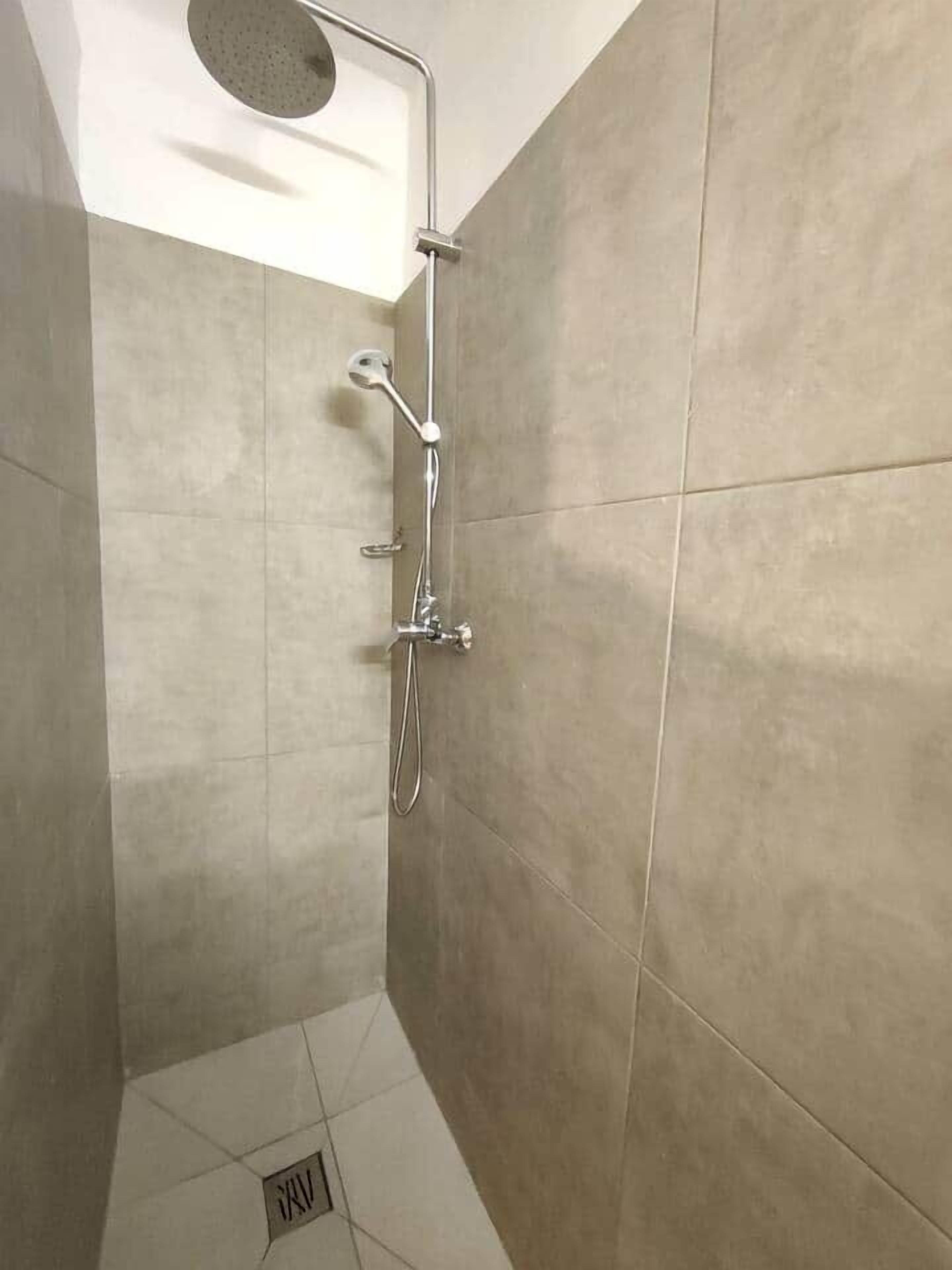 A shower with a handheld showerhead and a wall-mounted faucet.