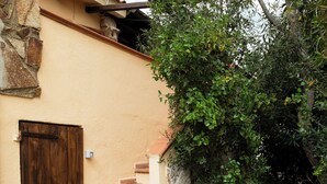 A stone building with a wooden door and a staircase leading to a second floor. - Casa Girgolu by Wonderful Italy (San Teodoro)