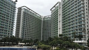 A high-rise hotel with multiple balconies and a swimming pool area. - Santorini Suites (Parañaque)