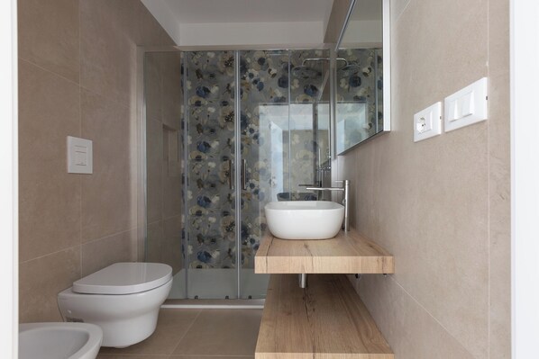 A modern bathroom with a glass shower enclosure, a white toilet, and a wooden vanity with a sink.