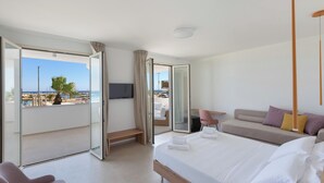 Una habitación de hotel moderna con balcón, cama, sofá y escritorio.