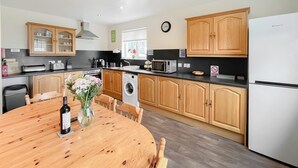 Une cuisine avec des meubles de rangement en bois, un four à micro-ondes, un lave-linge et une table à manger avec des chaises.