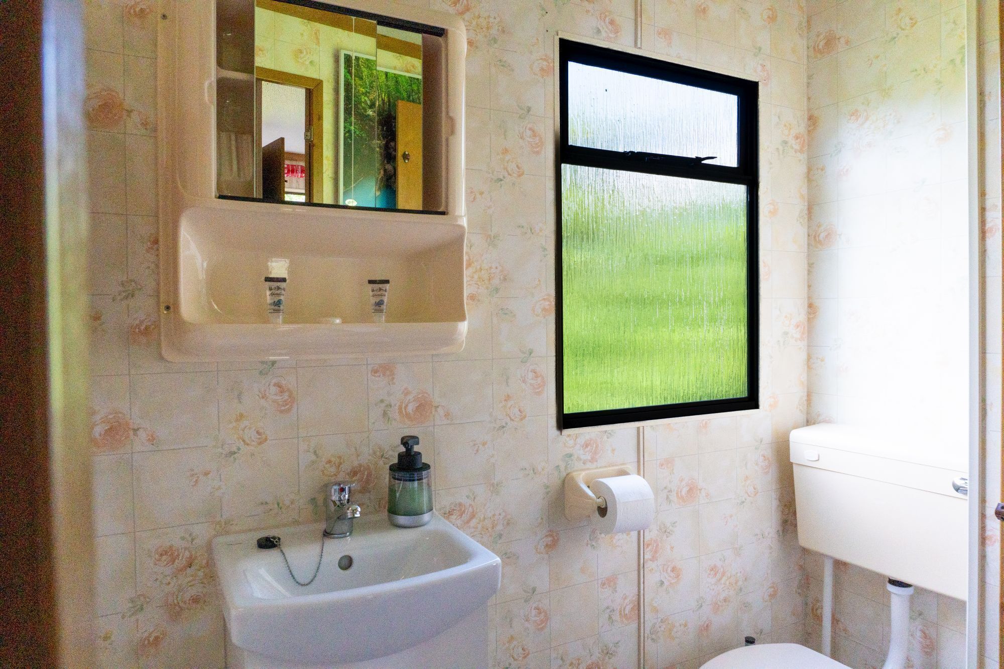 Een badkamer met een wastafel, spiegel en toilet.