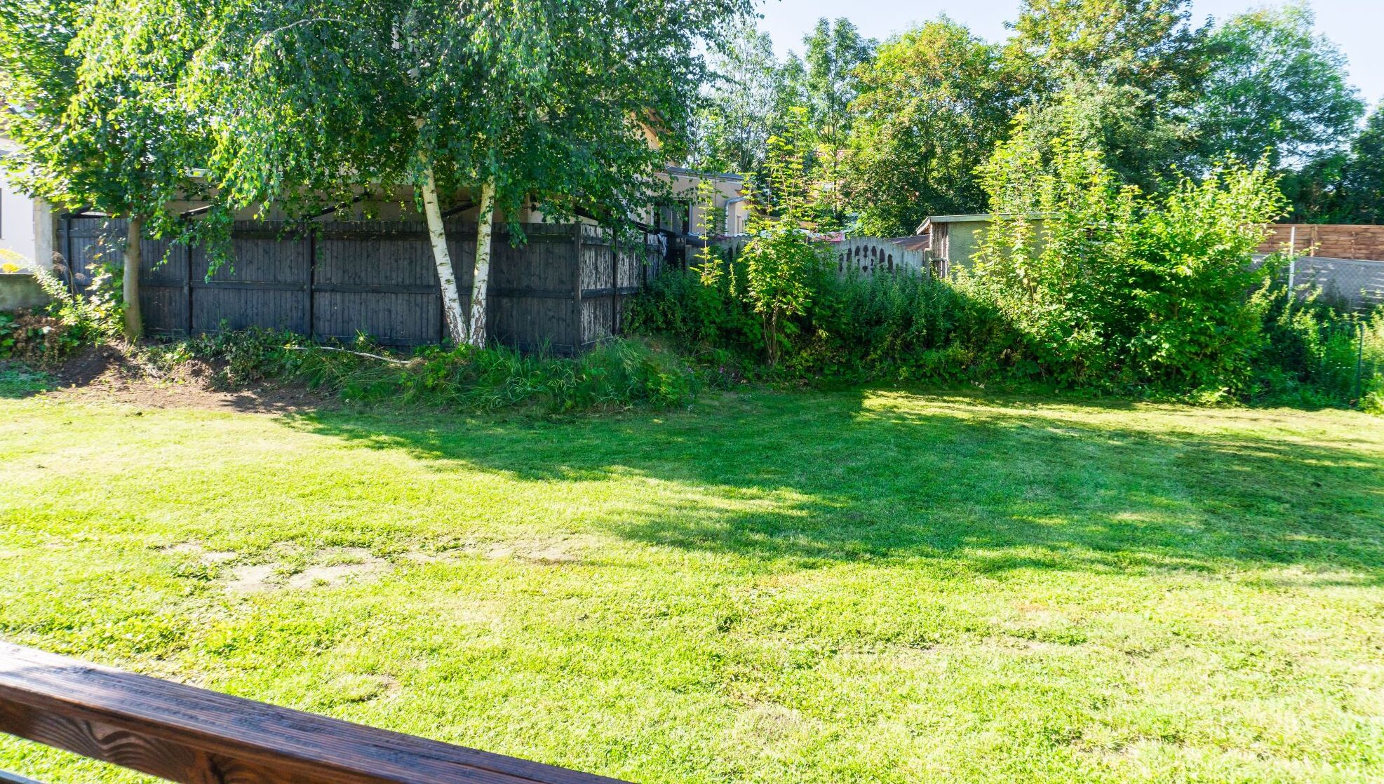 Ein Garten mit Holzzaun, Bäumen und Rasen.
