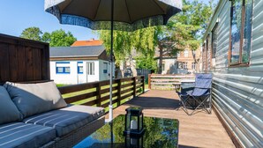 A wooden deck with a sofa, a table, and a chair. - Base Camp for the Harz and City Tours Leipzig, Magdeburg, Dessau, Quedlinburg... (Gröbzig)