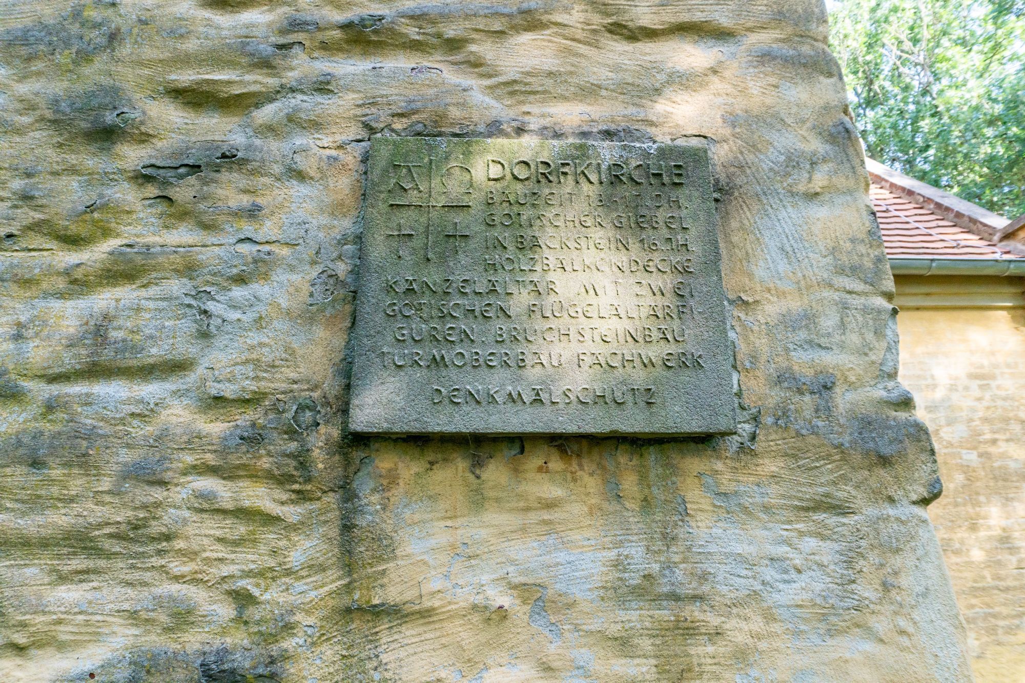 A stone plaque with inscriptions, mounted on a weathered stone wall.
