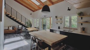 Een ruime woonruimte met een houten eettafel, een trap en een keuken met inbouwplanken.