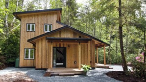 Een houten chalet met een veranda en een trap naar de ingang.
