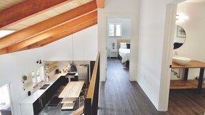 Een moderne keuken met houten balken, een eethoek en een slaapkamer met een groot raam.