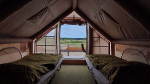 Une tente équipée de deux lits et offrant une vue sur l’extérieur.