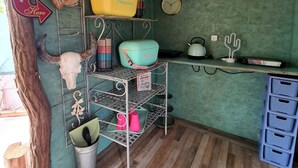 Une cuisine rustique avec un plancher en bois, une étagère en métal et une horloge au mur.