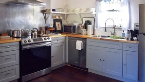 Una cocina moderna con electrodomésticos de acero inoxidable, armarios grises y una encimera de madera.