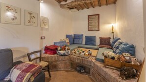 Una sala de estar acogedora con chimenea de piedra, un banco de madera con juguetes suaves y un sofá azul con cojines estampados.