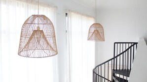 Una escalera con barandilla negra y una lámpara colgante de diseño tejido.