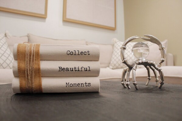 A stack of books titled 'Collect Beautiful Moments' on a table with a decorative metal sculpture. - Aqua Dream Hideaway at Aquatika Beach Villas (Loiza)