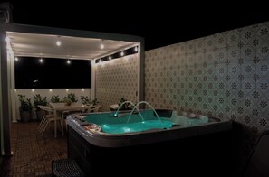 A hot tub area with a table and chairs, surrounded by patterned wallpaper and a tiled floor. - Aqua Dream Hideaway at Aquatika Beach Villas (Loiza)