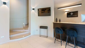 Un intérieur moderne avec un escalier, un comptoir d’accueil et deux tabourets de bar.