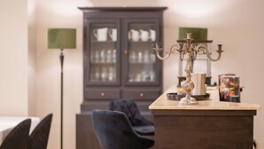 Un coin repas avec une table en bois foncé, deux chaises, un buffet aux portes vitrées et un chandelier posé sur la table.