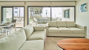 A modern living room with a sofa, a dining table with chairs, and a large window.