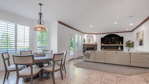 A modern living room with a fireplace, a large sectional sofa, and a dining area with a table and chairs.