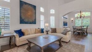 A spacious living room with a large sectional sofa, a wooden coffee table, and a dining area with a table and chairs.
