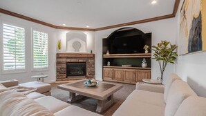 A living room with a fireplace, built-in shelves, and a large flat-screen TV.