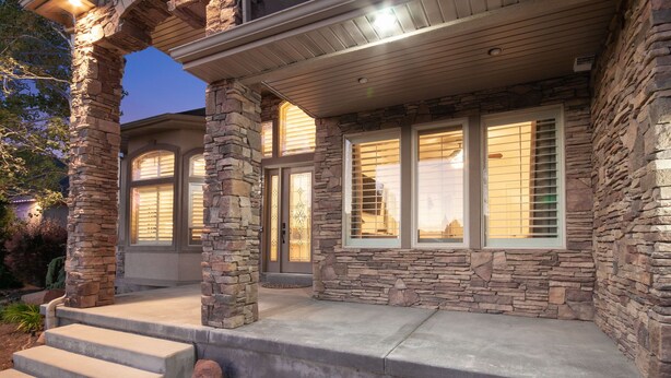 A stone-clad house with a covered porch and large windows.