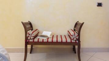 A wooden bench with striped cushions and a book on it, against a plain wall.
