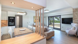 A modern kitchen with white cabinets, a wooden countertop, and stainless steel appliances. - Casa Platanias Bridge (Πλατανιά)