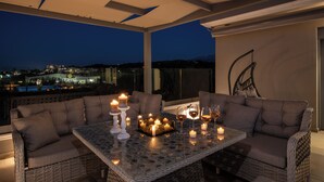 A rooftop terrace with wicker furniture, candles, and glasses of wine. - Casa Platanias Bridge (Πλατανιά)