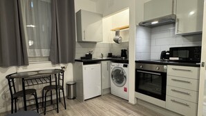 A compact kitchen with a washing machine, oven, and microwave. - Stylish studio/ Harrods /South Kensington /Chelsea/Central London (London)
