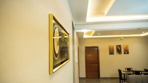 Un interior moderno con una obra de arte enmarcada en la pared, una puerta de madera y un área de comedor con sofá y mesa.