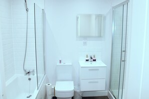 A modern bathroom with a bathtub, toilet, and glass shower enclosure. - Spacious 2 Bedroom Apartment in Margate (Margate)