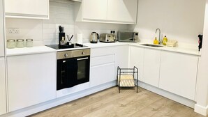A modern kitchen with white cabinetry, a built-in oven, a microwave, and a sink. - Spacious 2 Bedroom Apartment in Margate (Margate)